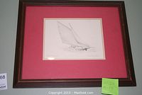 Framed art print of a sailboat titled Fast Friendship with a red mat and dark wooden frame.