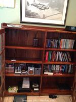 Wooden bookshelf with multiple compartments, containing books primarily on right side along with some media items below.