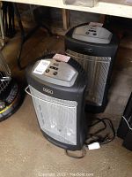 Two black and silver Holmes electric heaters model HQH347 placed on the floor showing front and side views.