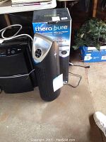 Therapure air purifier unit shown next to its original box in a cluttered room.