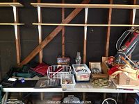 Table with various items including folding chairs backing the table, collectible buttons in containers, chocolate fondue fountain box, glass oil lamp, snow globe, and other household items.