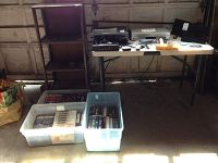 Full lot setup showing boxes of movies, electronics on table and shelves.