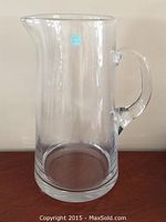Front view of clear glass pitcher with handle and spout, clean and in good condition.
