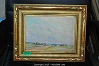 Gold-framed landscape oil painting displayed on chair