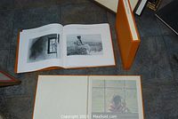 Orange clothbound book and matching slipcase displayed on floor tiles