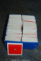 Box containing many small pin display cards arranged upright with one card showing a single triangular pin.