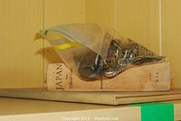 Plastic bag of assorted metal badges resting on top of a hardcover book titled “Japan Official Guide”