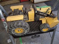 Close up side profile of large Tonka excavator toy showing large tires and moving arm with bucket