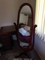 Front view of the wooden framed oval floor mirror with dark polished finish.