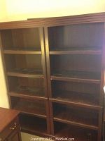 Front view of the two matching dark wood bookcases with glass doors showing five adjustable shelves inside each.