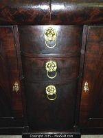 Close-up photo of the three center drawers with ornate brass lion head ring pulls on a dark wood dresser.