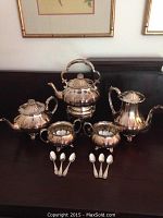 Overview photo showing the entire tea set including three teapots, creamer, sugar bowl, and six spoons.