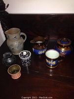 Seven mixed decorative pottery and china items displayed on dark wooden surface.