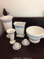Overview of complete set showing a large bowl, three vases of different shapes and sizes, and two candleholders in front on wood surface