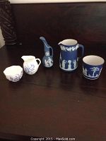 Five small ceramic pieces arranged on dark wooden surface including Wedgwood Jasperware and Coalport Bone China pieces.