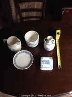 All five Wedgwood items displayed on a table with measuring tape for scale, showing pitcher, ewer, bowl, stand, and box.