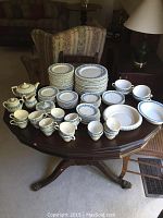 Wide view of full set on table showing plates, bowls, cups, serving pieces