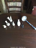 Overview of five small bird figurines and one Chinese-themed ladle on table to show the number of items and their relative sizes and colors.