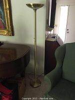 Full view of the brass floor lamp next to furniture showing its height and design.