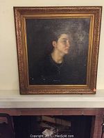 Full view of the framed oil painting showing a dark-haired woman in profile facing right. Canvas has wear, cracks, and chip damage visible.