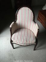 Front view of carved wood upholstered chair with plaid fabric cover
