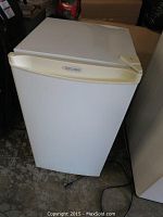 Front view of the white Diplomat bar sized refrigerator showing the door and logo on handle.
