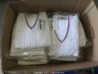 Box filled with 11 white medium size tennis sweaters folded and individually packaged in clear plastic.