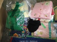 Overview of assorted packaged children's sweaters in various colors and patterns including pink and green.
