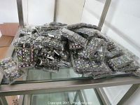 Multiple individually packaged bracelets stacked on a glass shelf; display shows the quantity and packaging of the lot