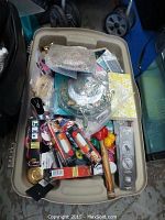 View of the entire lot in a plastic bin with various household items including kitchenware and packaged bulbs.