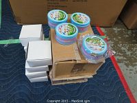 Overview of 6 round blue cheerleader necklace cases stacked on a box with 5 white boxes beside them