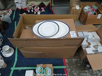 Boxes containing the 45-piece Royal Vienna bone china set, showing white plates with double blue rims.