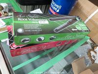 Photo showing boxed Hot Styler Root Volumizing flat irons stacked on a table.