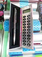 Open silver pen and calculator case showing inside black lined compartment with pen and calculator