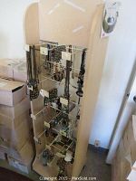 Wooden jewelry display stand with multiple metal rods holding assorted hanging necklaces and bracelets, view from the front.