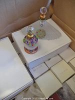 Box of new perfume bottles with stacked white boxes inside and two displayed bottles on top.