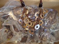 Photo showing multiple necklaces packed in plastic bags within a box.