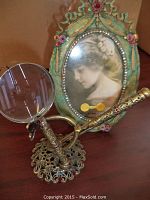 Close-up of ornate oval frame with vintage portrait surrounded by rhinestones and painted floral ribbons