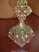 Ornate frosted glass perfume bottle with gold-tone metal filigree stopper embellished with faux pearls and amber rhinestones