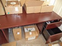 Full view of desk showing multiple drawers, storage compartments, and a flat top surface with some boxes and other items on it.