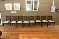 View of all eight chairs in a row against a wall