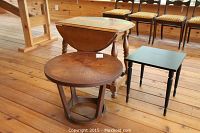 Photo shows three wooden tables on wooden floor: Lane teak round table front left, small drop leaf table behind, small black square table front right.