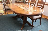 Full view of extended table with leaves installed and runner laid across top, chairs in background