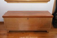 Front view of closed chest showing light wood finish and keyhole