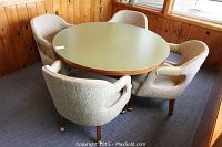 Set includes round dining table and four upholstered chairs shown from angle