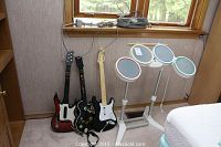 Rockband and Guitar Hero guitars with two Rockband drum sets leaning against a wall