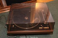Dual CS-1242 turntable with transparent dust cover lowered, wooden plinth on carpeted floor