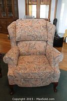 Front view of the floral upholstered wing back arm chair, showing the cushioned seat and back with wood legs.
