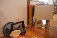 Front view showing 4 beige laminate TV tables on wooden stand, 2 additional wooden TV tables, and various decorative items on floor arranged in front of a mirror.