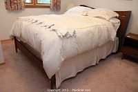 Full view of assembled double bed with mattress, box spring and bedding in bedroom